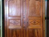 a wooden armoire in a room with a green wall