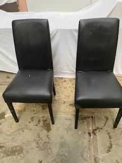 une paire de chaises de salle à manger en cuir noir avec des pieds noirs