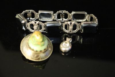 a silver bracelet with a green flower on it