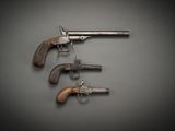 trois vieux revolvers accrochés à un crochet fixé au mur