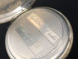 a silver pocket watch sitting on top of a black table