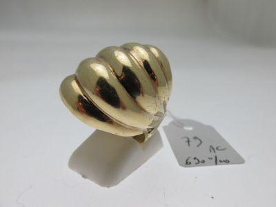 une bague en or posée sur une surface blanche, avec une étiquette de prix