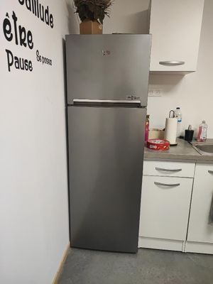 a stainless steel refrigerator in a kitchen with a sign on the wall