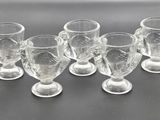 six clear glass cups with a handle on a black surface