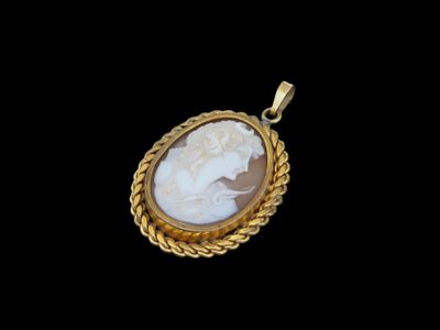 un pendentif camée doré et blanc représentant le visage d'une femme
