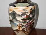 a vase with a painting on it sitting on a table
