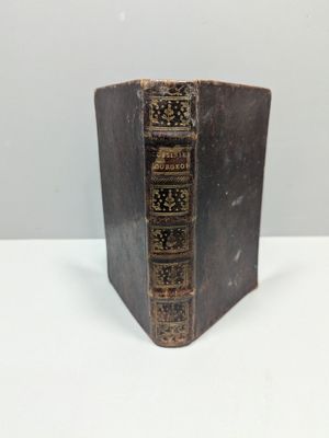 un vieux livre posé sur une table blanche à côté d'un mur blanc