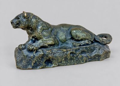 statue of a dog laying on a rock on a white surface