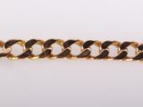 a close up of a gold chain bracelet on a white surface
