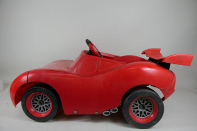 a red toy car that is sitting on a white surface