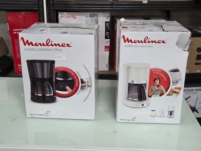 deux cartons contenant des machines à café posés sur une table en verre