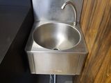 a stainless steel sink in the corner of a bathroom