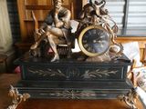 une statue représentant un homme assis sur une table, avec une horloge