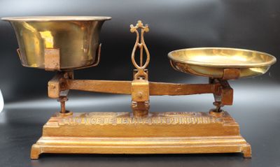 une balance en or posée sur une table, avec deux coupelles dessus