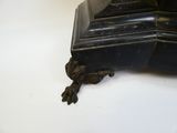 une horloge noire posée sur une table, sur fond blanc