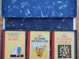 three children ' s books in a blue box on a wooden table