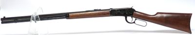 un fusil sur fond blanc, avec un support en verre pour le maintenir en place