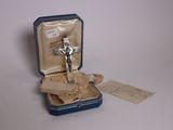 un petit crucifix en argent dans un écrin bleu