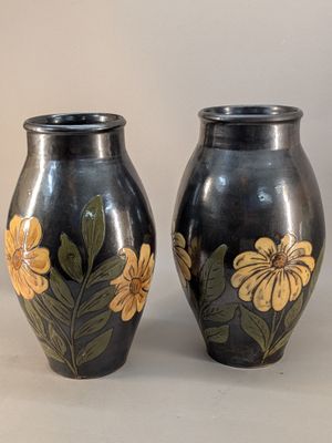 deux vases noirs sur lesquels sont peintes des fleurs jaunes