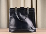 a black leather tote bag sitting on top of a wooden table