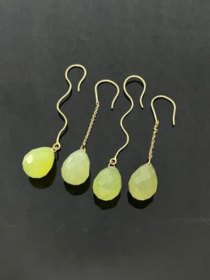 a set of four yellow jade tear earrings on a black background