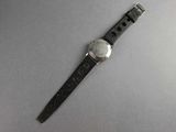 someone is holding a watch on their wrist on a white surface