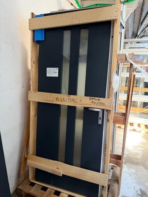 un réfrigérateur noir posé à côté d'une palette en bois dans une pièce
