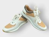 une paire de baskets pour femme, blanches et beiges, sur fond blanc
