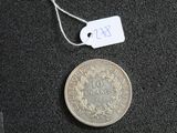 une pièce de monnaie sur laquelle est accrochée une étiquette de prix, à côté d'un bout de papier