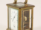 a small brass clock with a glass face on a white background