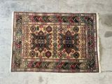 un vieux tapis posé à même le sol, sur fond blanc