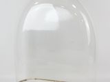 a clear glass clochet with a metal base on a white surface