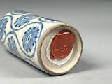 a small blue and white vase with a coin in it