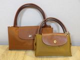 deux sacs à main marron et beige posés sur une table en bois