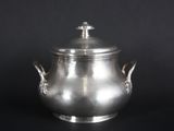 a silver pot with a lid on a black background