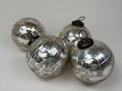 trois boules de Noël en verre argenté posées sur un fond blanc