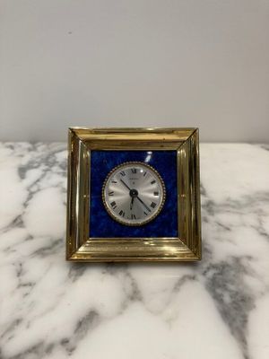 a small clock sitting on a marble counter top