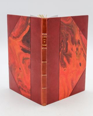 an open book with a red cover sitting on top of a white table