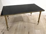 une photo d'une table basse noire et dorée posée sur un parquet