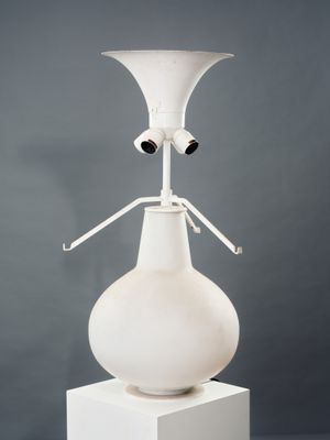 a white vase on a pedestal with two eyes on it