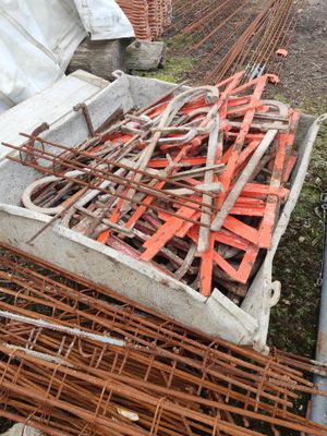 un tas de barres de fer rouillées posées par terre, à côté d'un autre tas de barres de fer rouillées