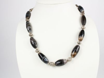 un gros plan d'un collier porté par un mannequin, composé de perles noires et blanches