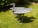 a metal bird that is standing in the grass