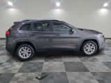 the gray jeep is parked in the garage on a checkered floor