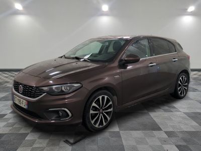 La voiture marron est garée sur un sol carrelé à damier.