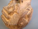 une petite statue représentant une personne assise sur un rocher