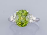 gros plan d'une bague avec une pierre verte entourée de diamants blancs