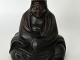 figurine de Bouddha assise sur une surface blanche, avec un fond blanc