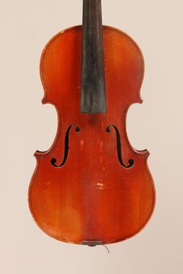 an old violin hanging from a string on a white wall