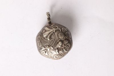 a silver pendant with a flower design on it